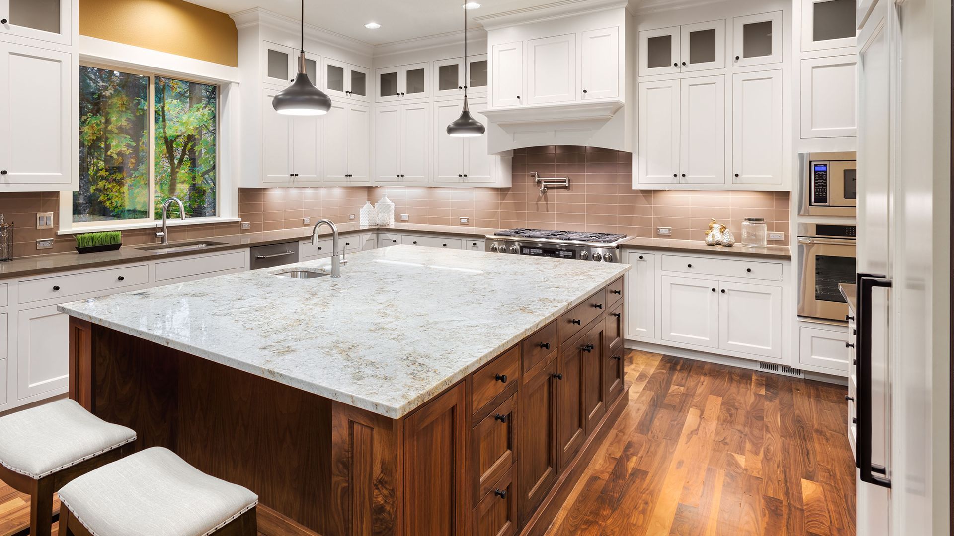 A kitchen with white cabinets , granite counter tops, and hardwood floors.