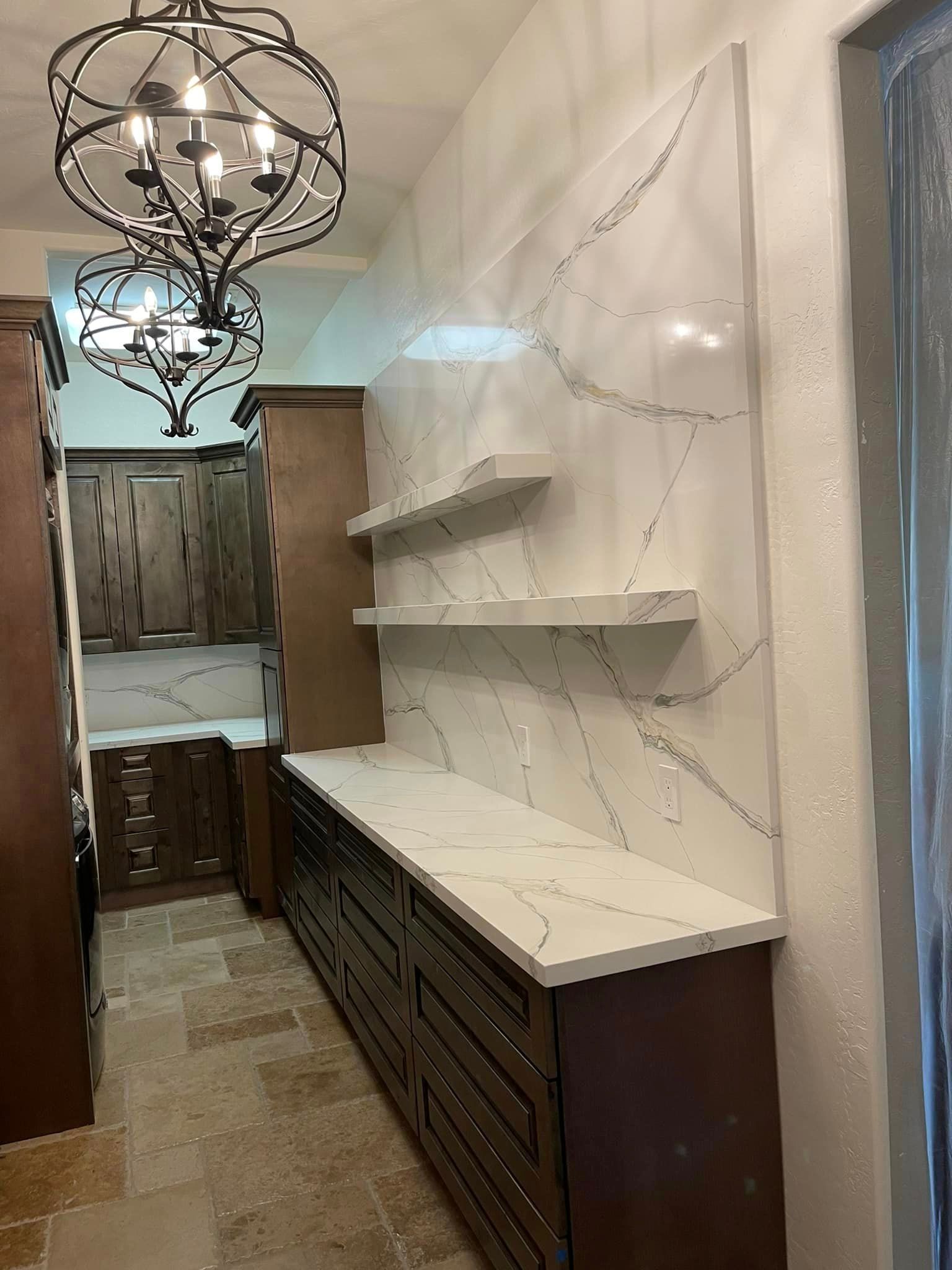 A kitchen with wooden cabinets and white counter tops and a chandelier hanging from the ceiling.