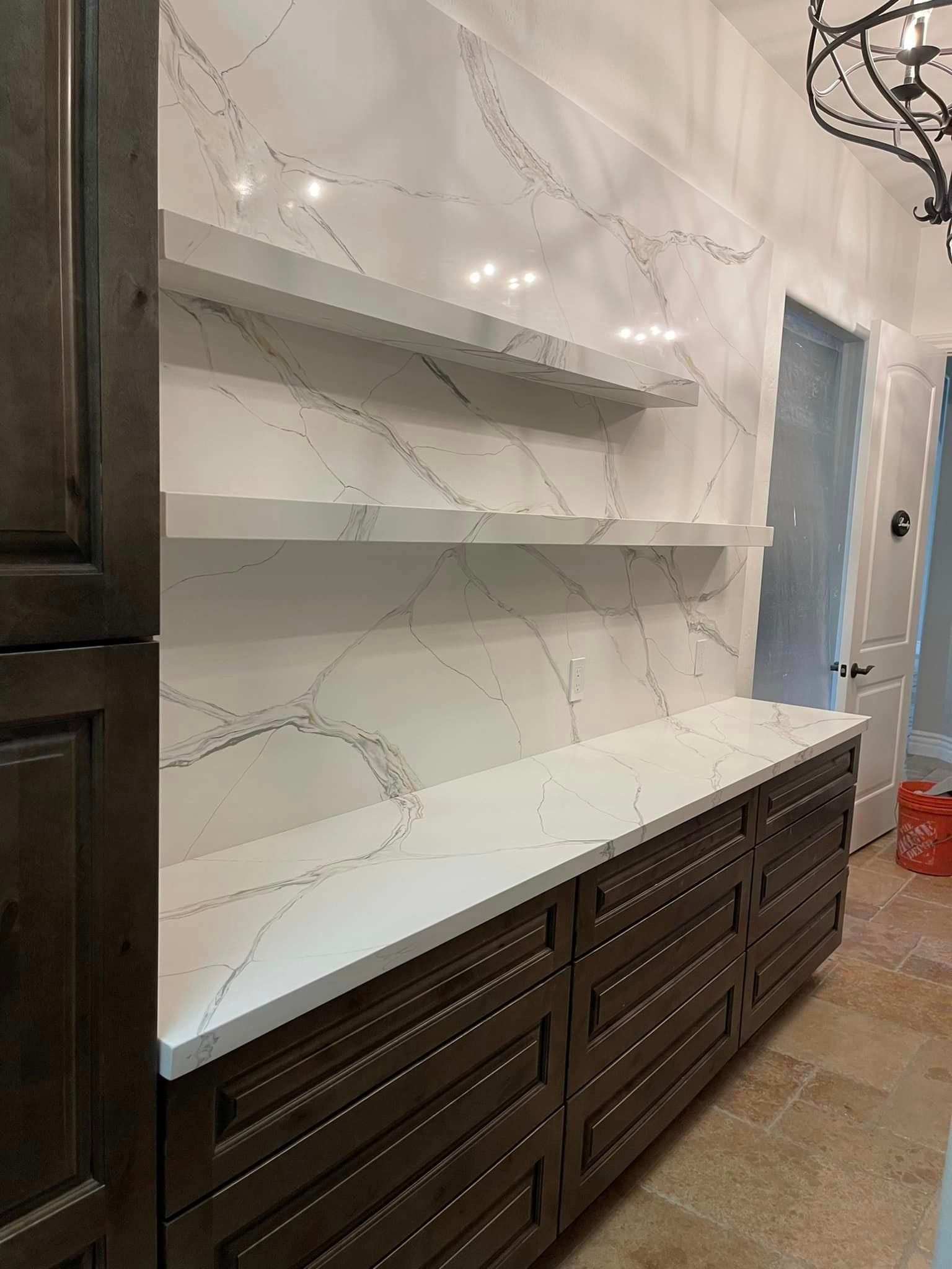 A kitchen with a long counter top and shelves.