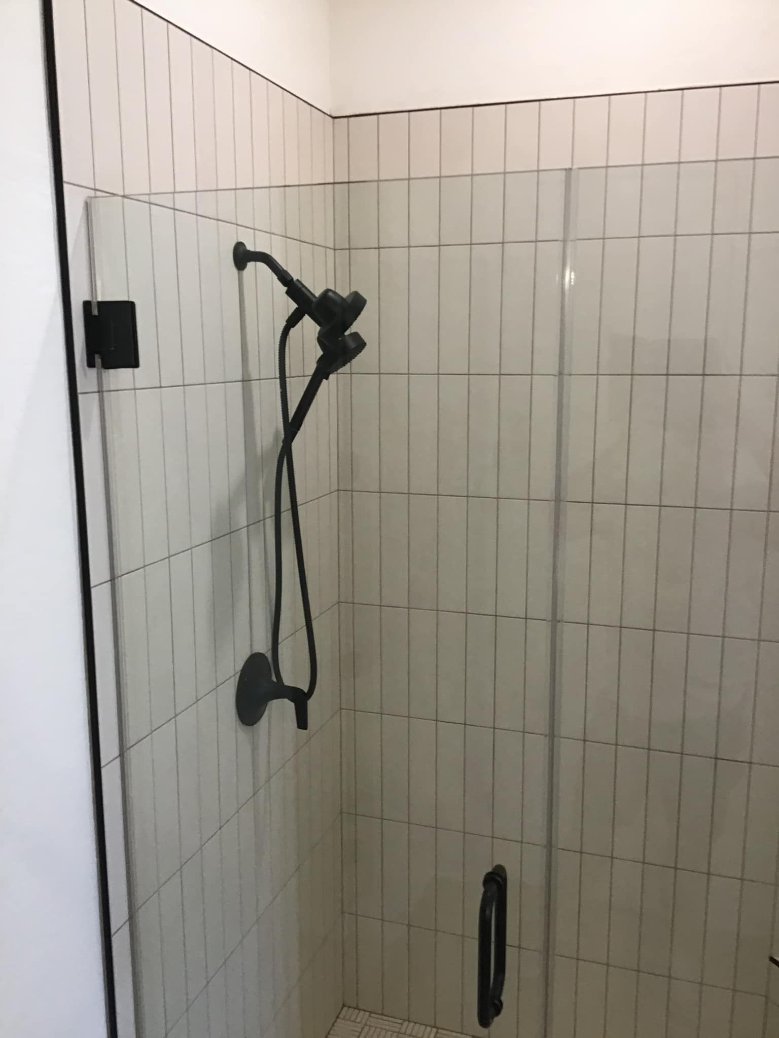 A shower with a black shower head and a glass door.