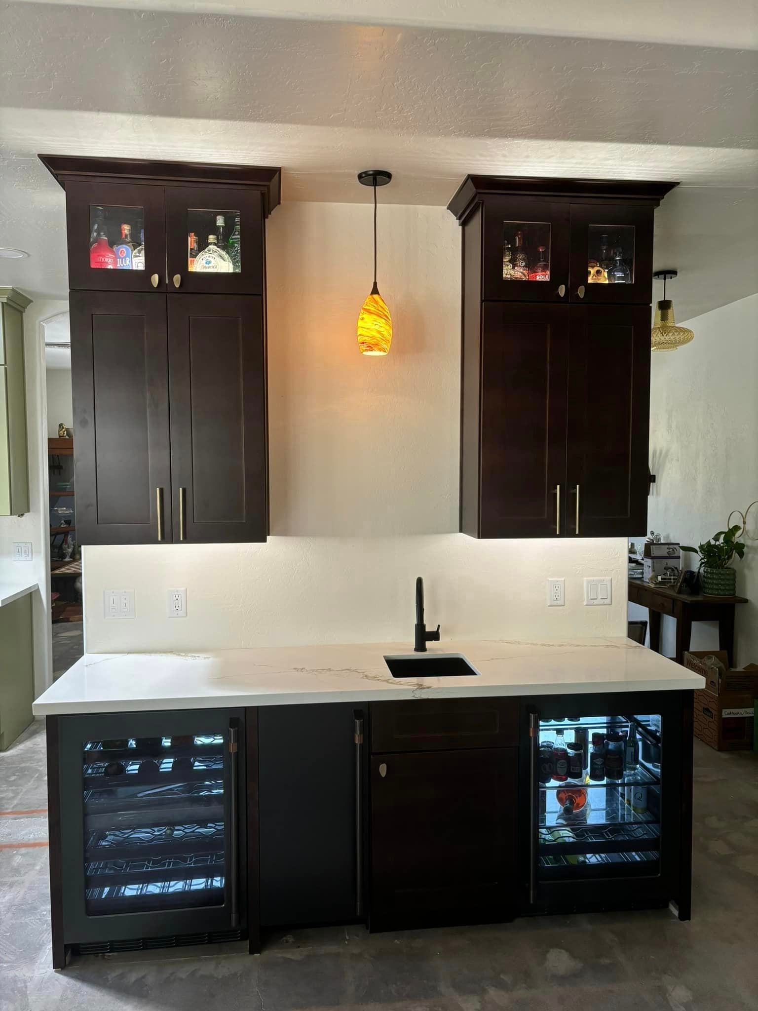 A kitchen with black cabinets, a sink, and a wine cooler.