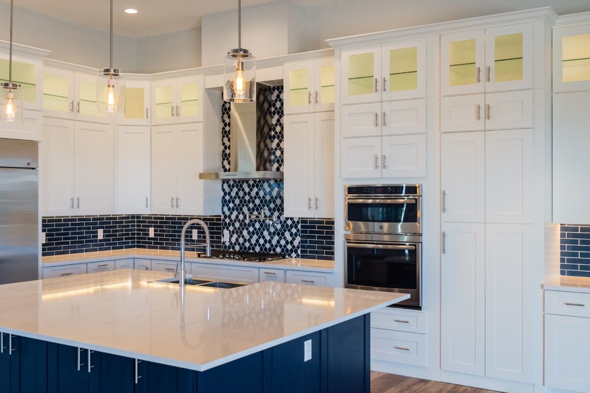A kitchen with white cabinets , blue cabinets , and stainless steel appliances.