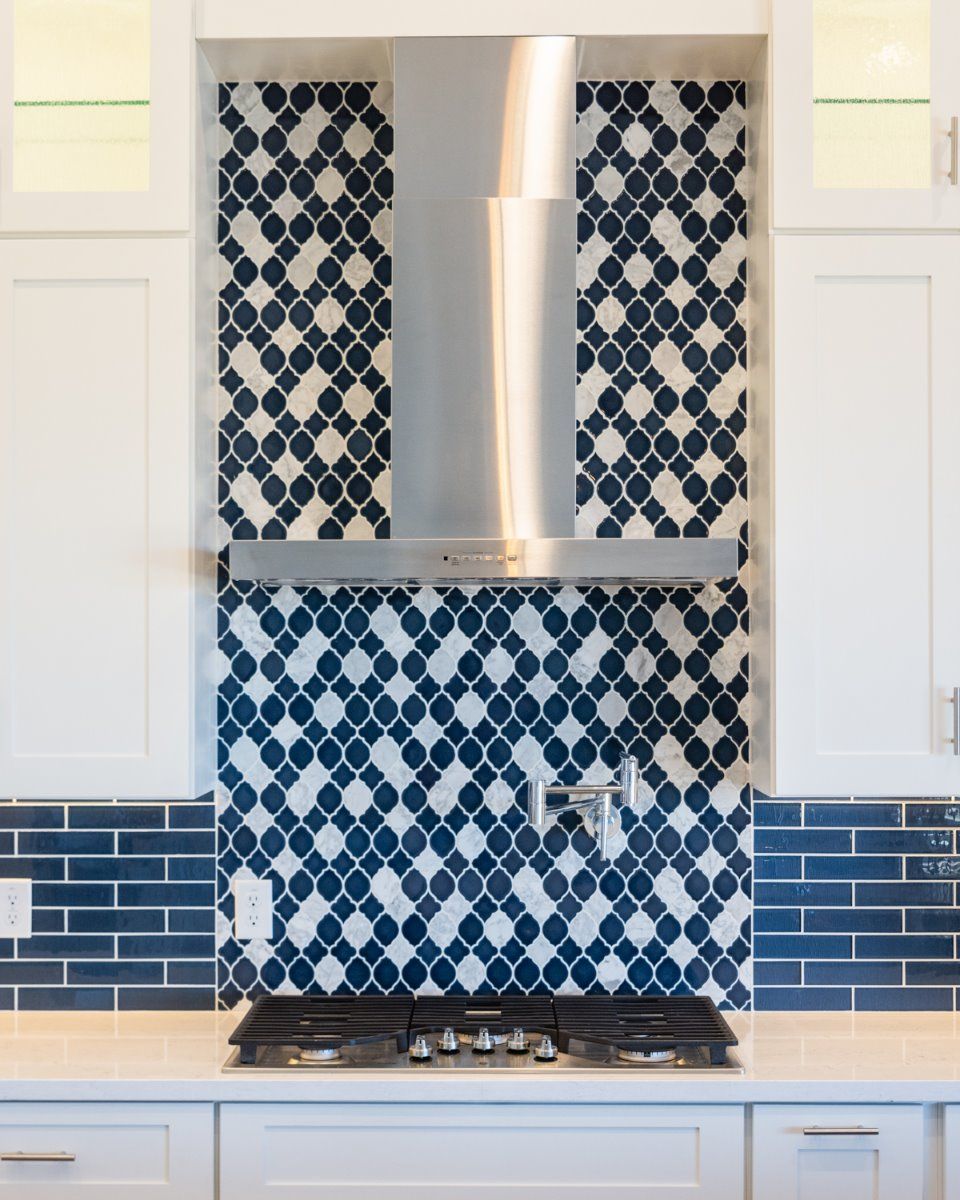 A kitchen with blue and white tiles and a stove top oven.