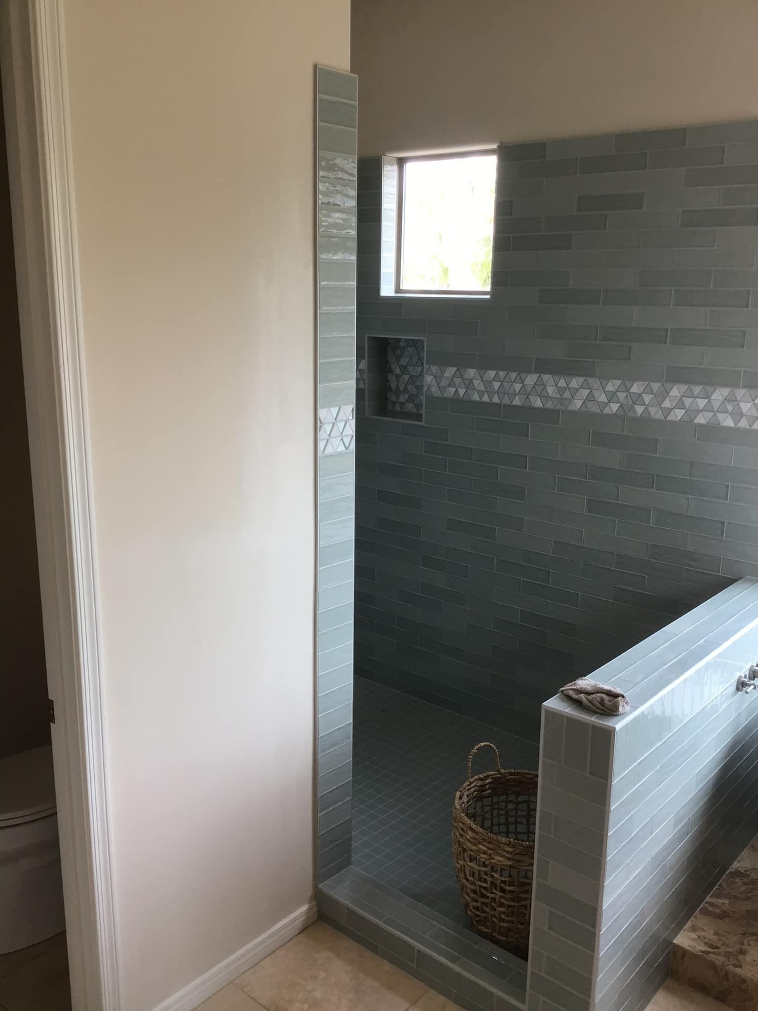 A bathroom with a walk in shower and a window.