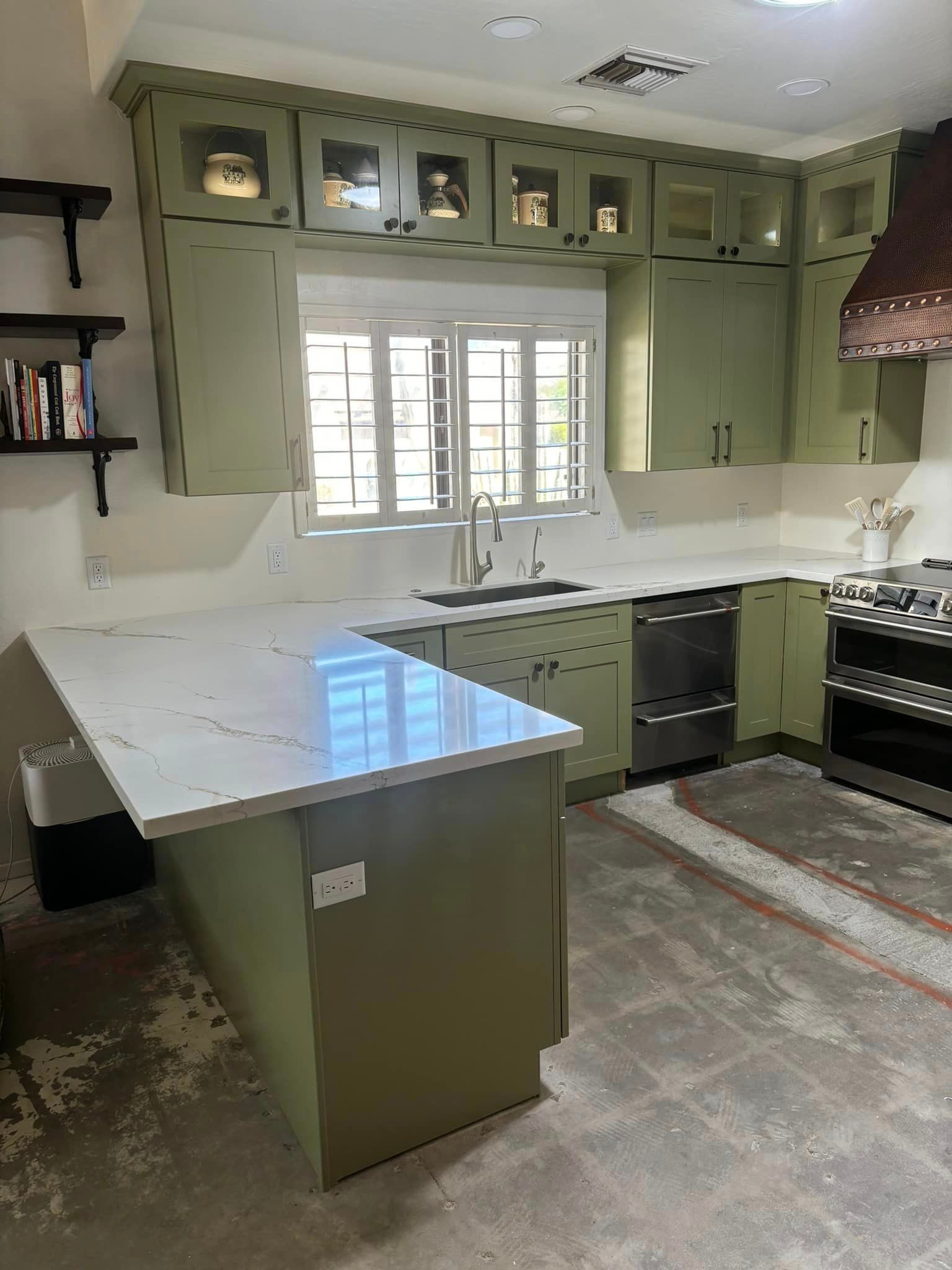 A kitchen with green cabinets and a white counter top.