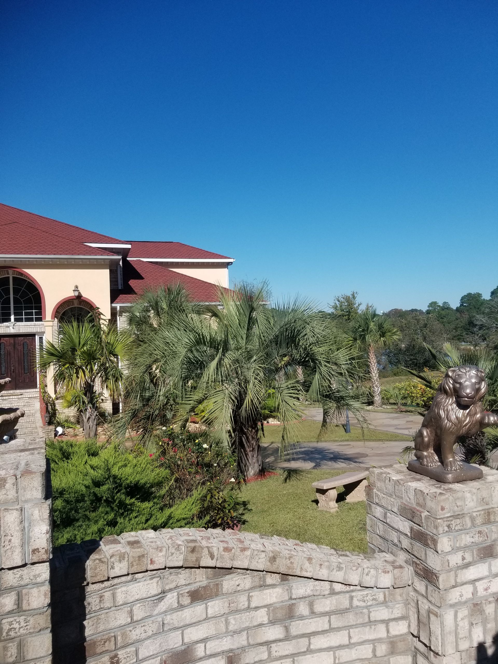a statue of a lion is sitting on a brick wall in front of a large house