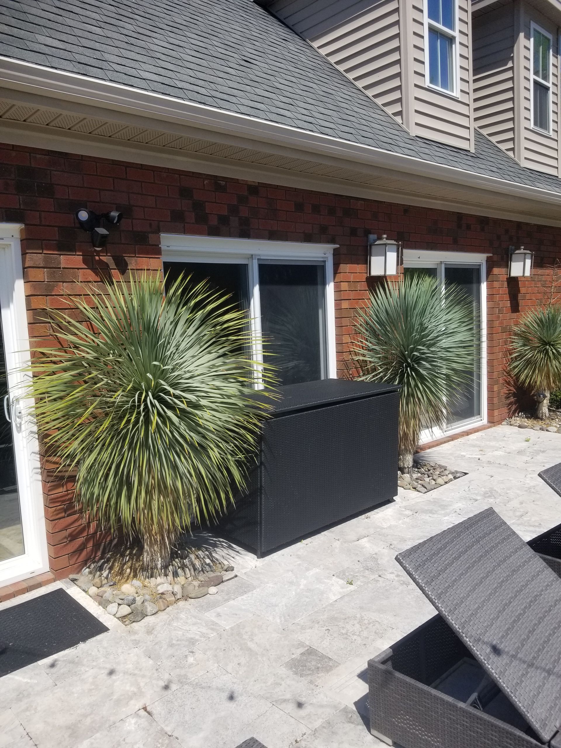 a brick house with a patio with chairs and plants