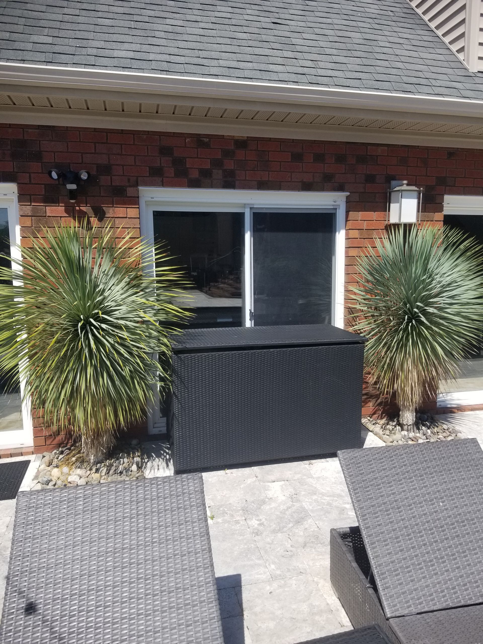 a patio with chairs and a black box in front of a brick house