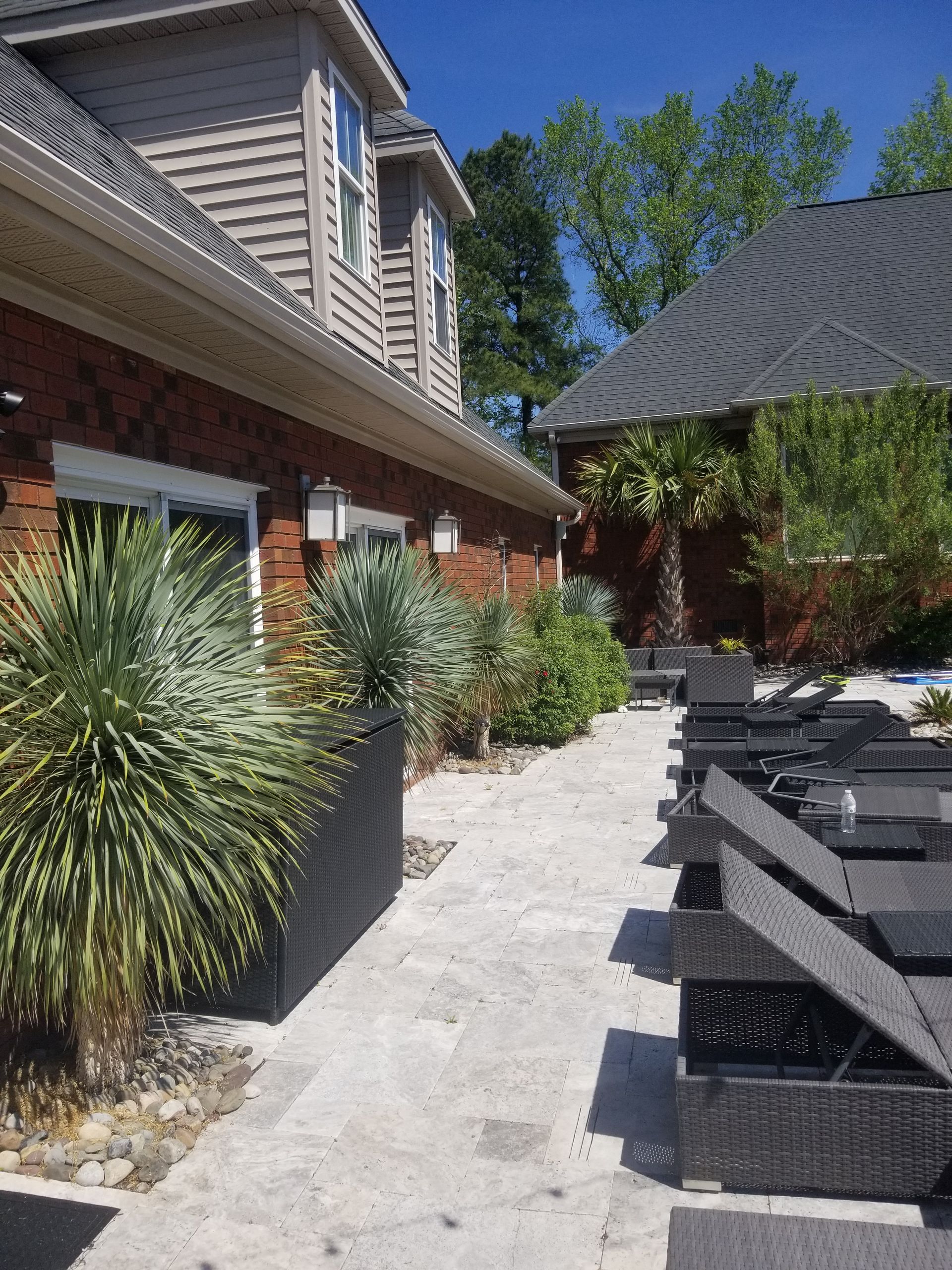 a patio with chairs and umbrellas in front of a house