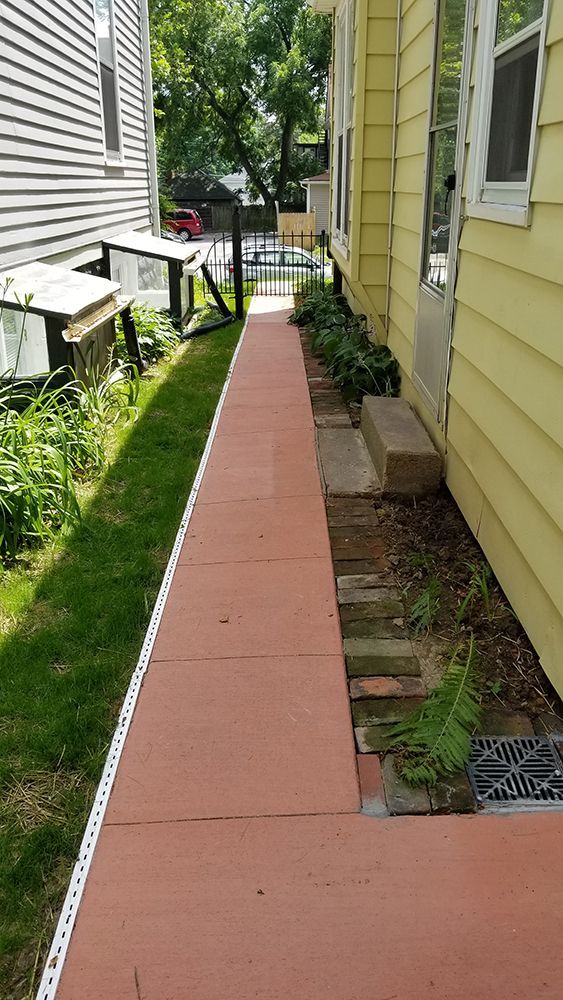 A sidewalk leading to a house with a yellow house in the background.
