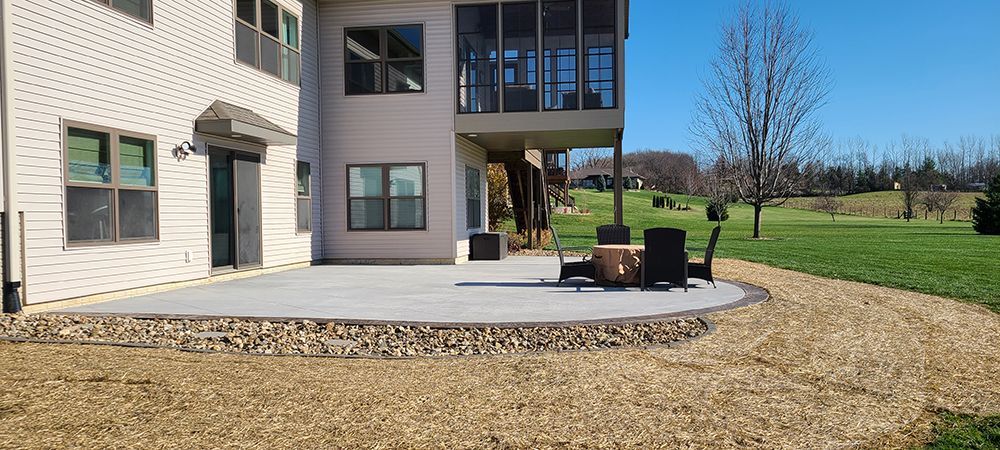 A large house with a patio and chairs in front of it.
