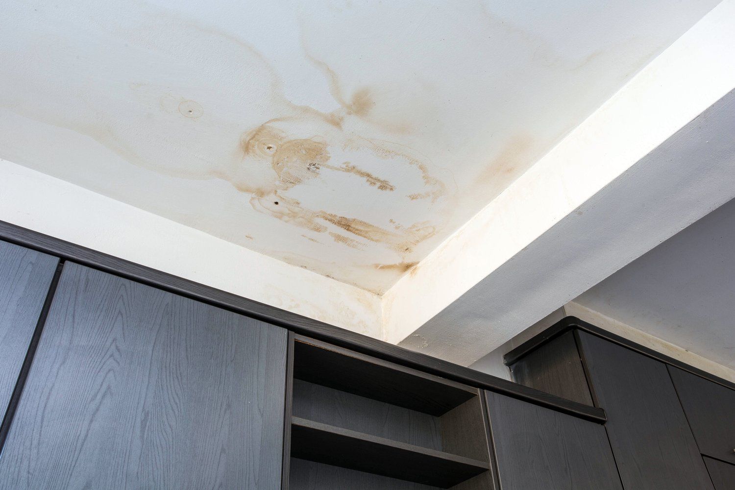 a ceiling with water stains on it in a room with cabinets
