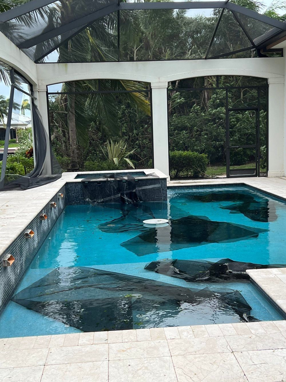 a large swimming pool is surrounded by a screened-in area 