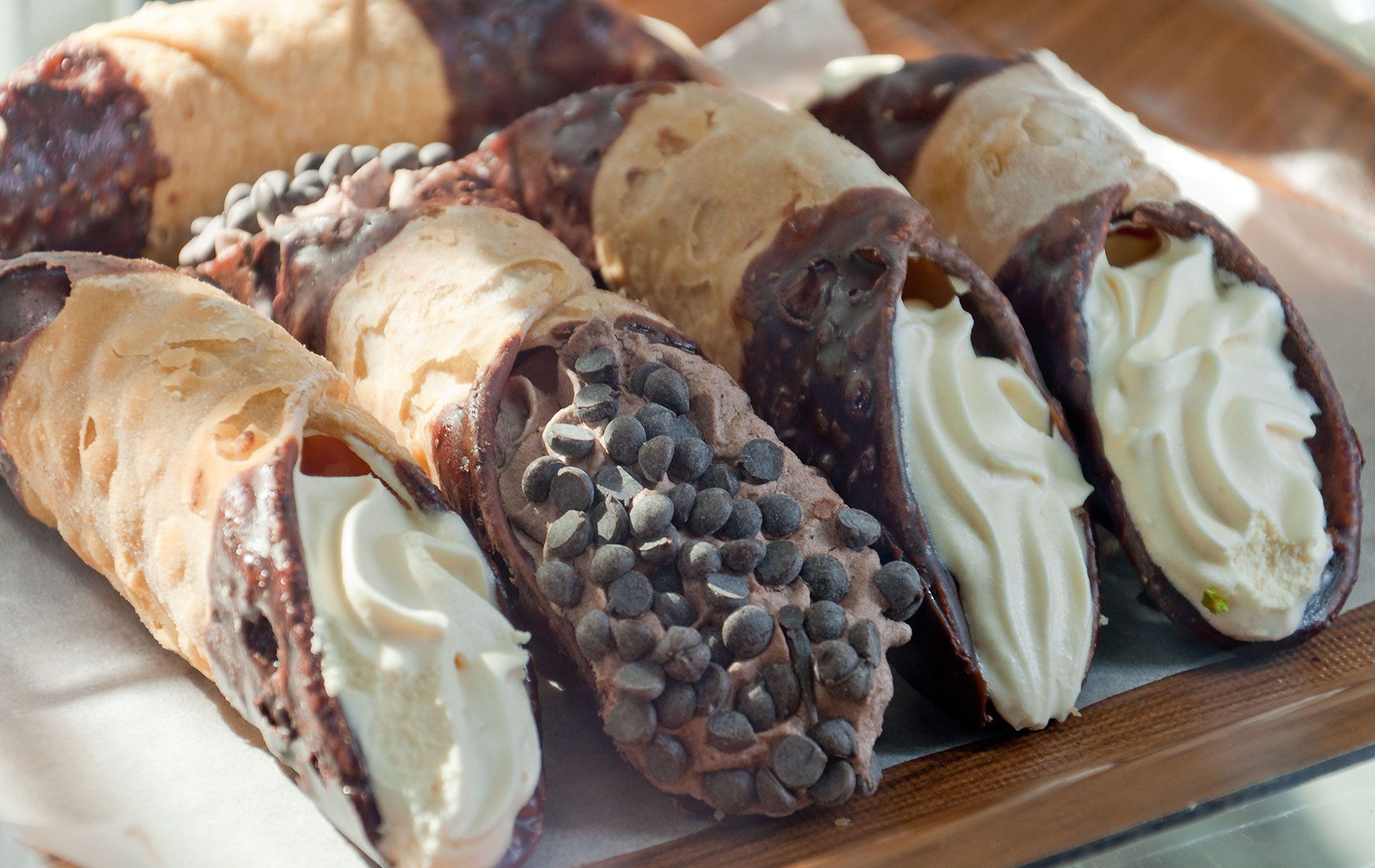 A tray of cannoli with different flavors and toppings