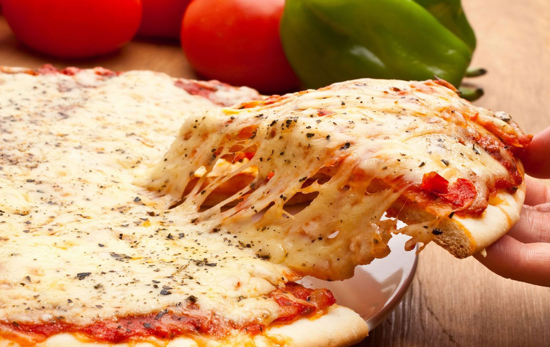 A person is taking a slice of pizza from a plate.