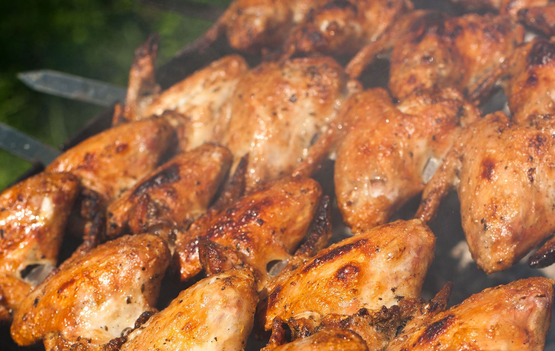 Chicken wings are being cooked on a grill.