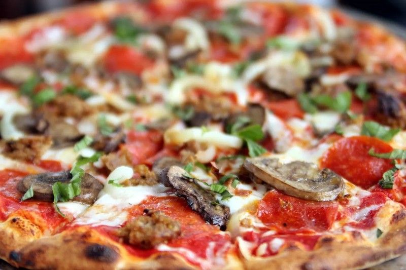 A pepperoni pizza is sitting on a table surrounded by ingredients.