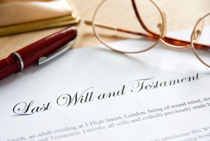Last Will and Testament document with pen and glasses on a table.