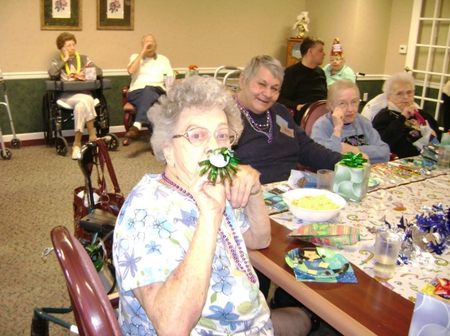Residents at a dining table, smiling and eating at a decorated indoor gathering