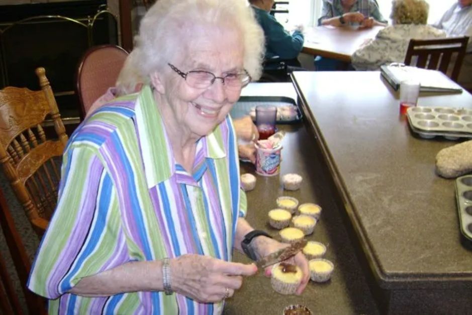 Smiling woman in a striped shirt preparing cookies in a kitchen at a counter