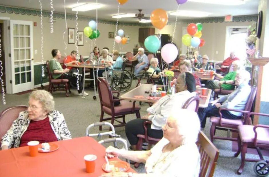Residents socializing at a decorated community room party with balloons and tables