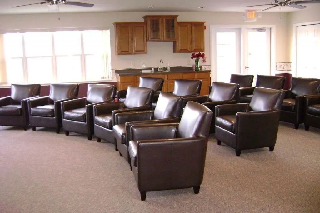 Empty lounge with dark leather chairs and a small kitchenette area in the background