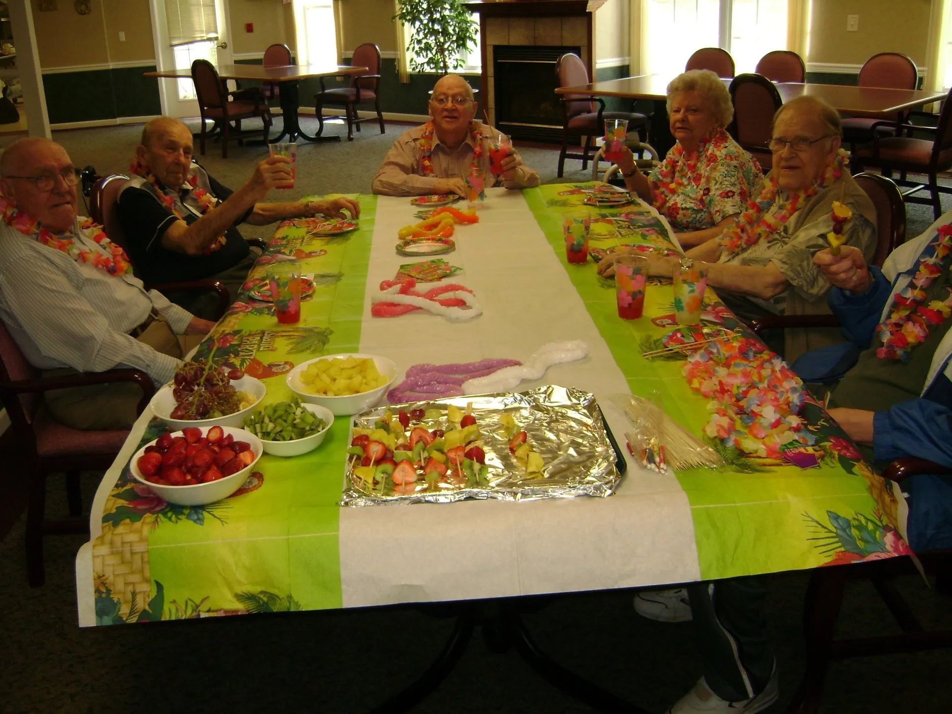 People seated around a long table with snacks and drinks at a social gathering