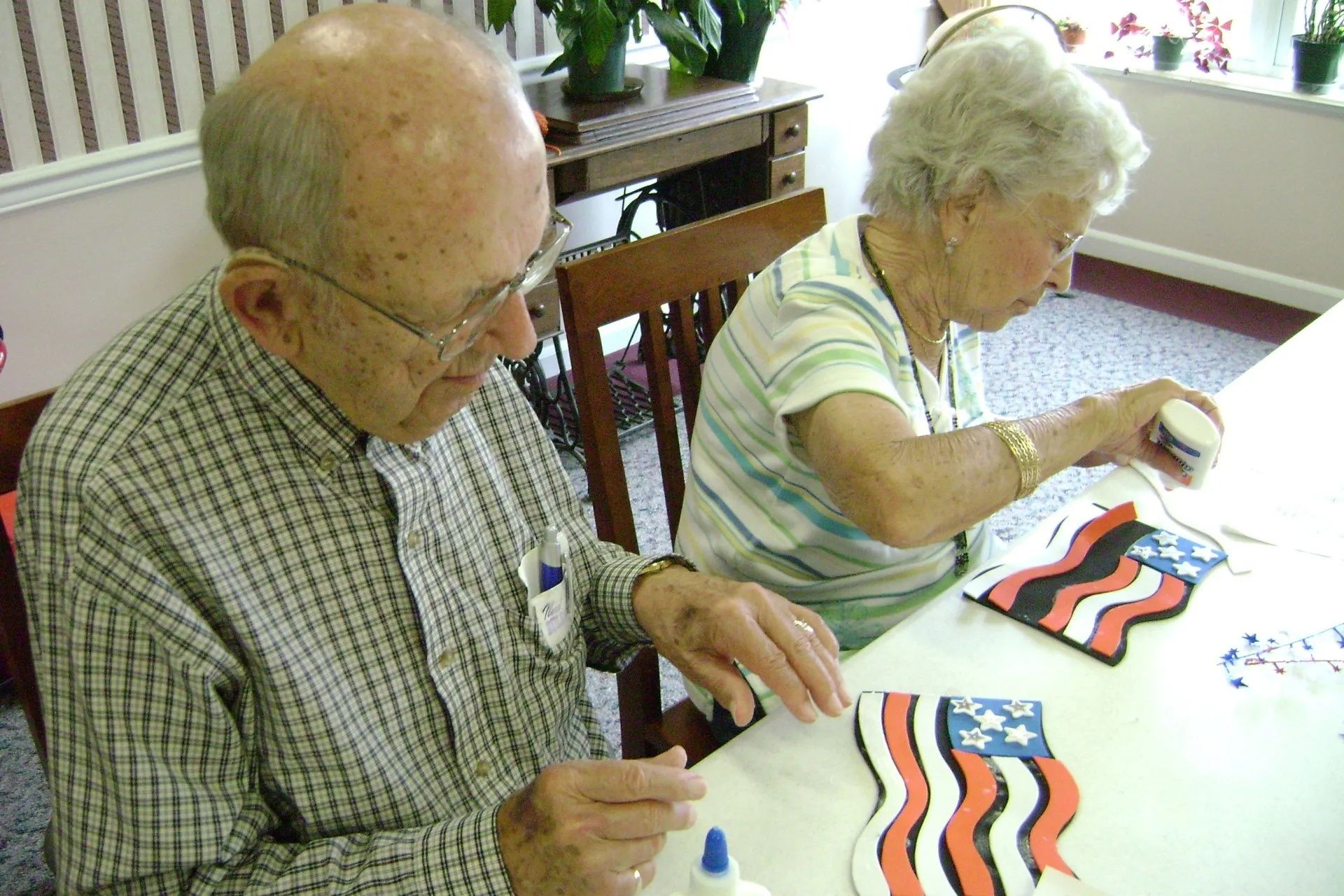 Two people painting colorful wavy patterns at a table in a bright room