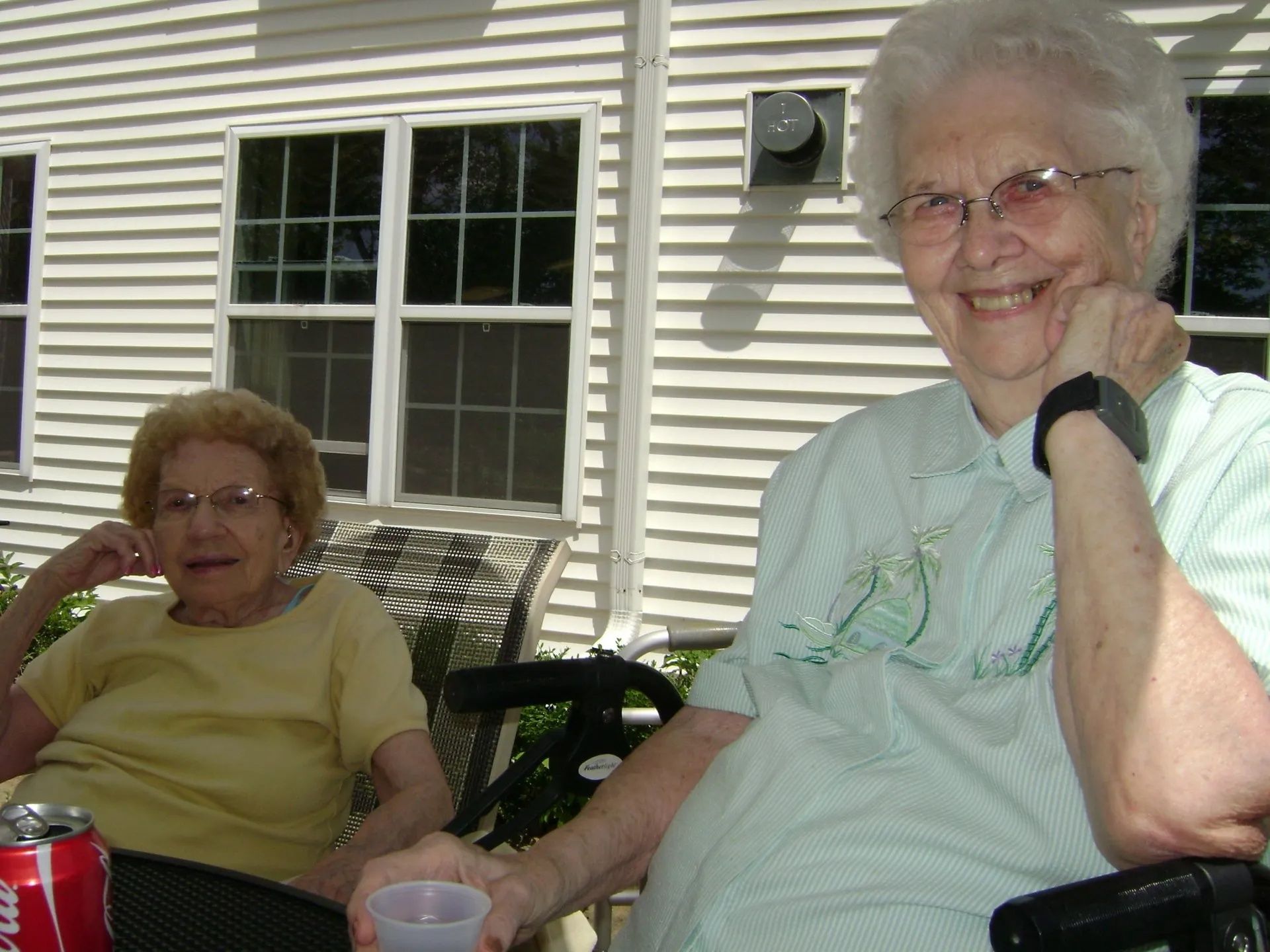 Two women sitting on a porch, smiling in the sunlight
