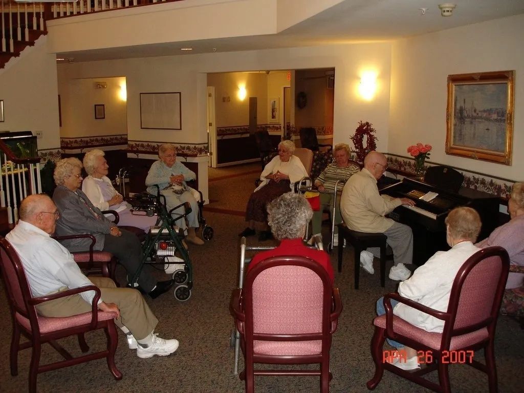People seated in a cozy lounge, chatting in a warmly lit room with chairs and a fireplace.