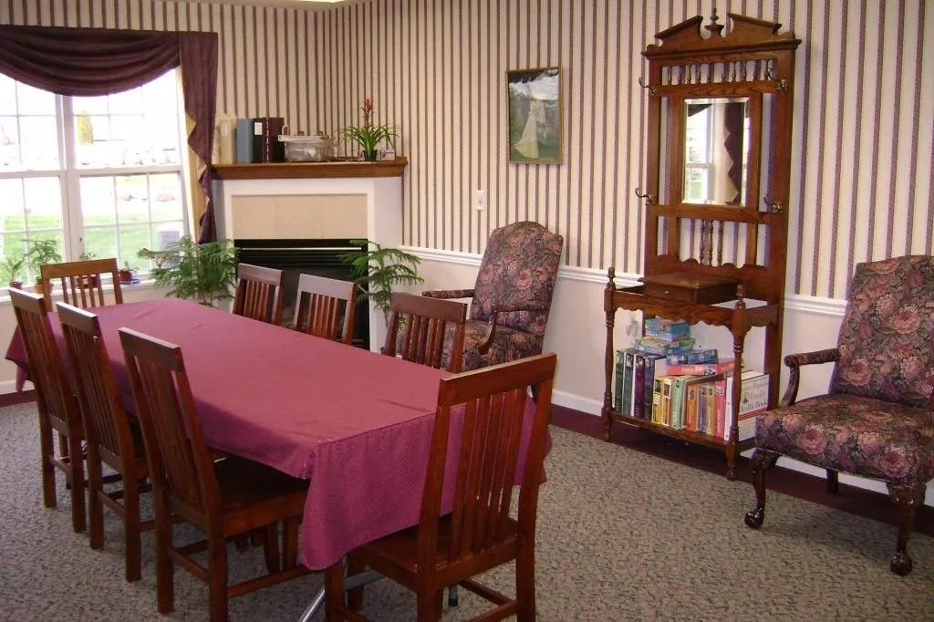 Dining room with a set table, maroon chairs, striped wallpaper, and a china cabinet.
