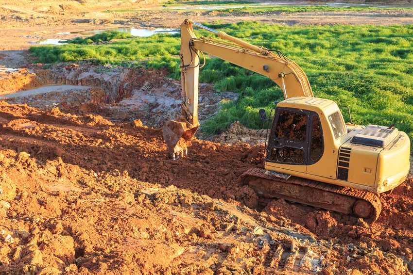A yellow excavator is digging a hole in the dirt.