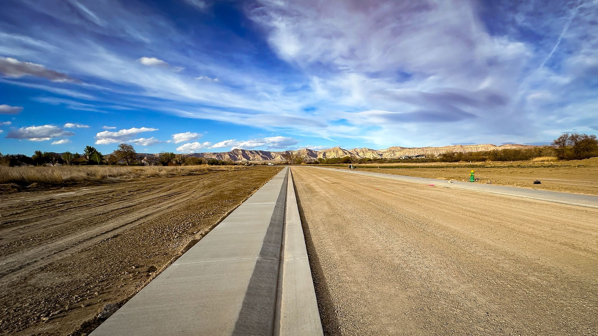 A concrete walkway in the middle of a dirt road.
