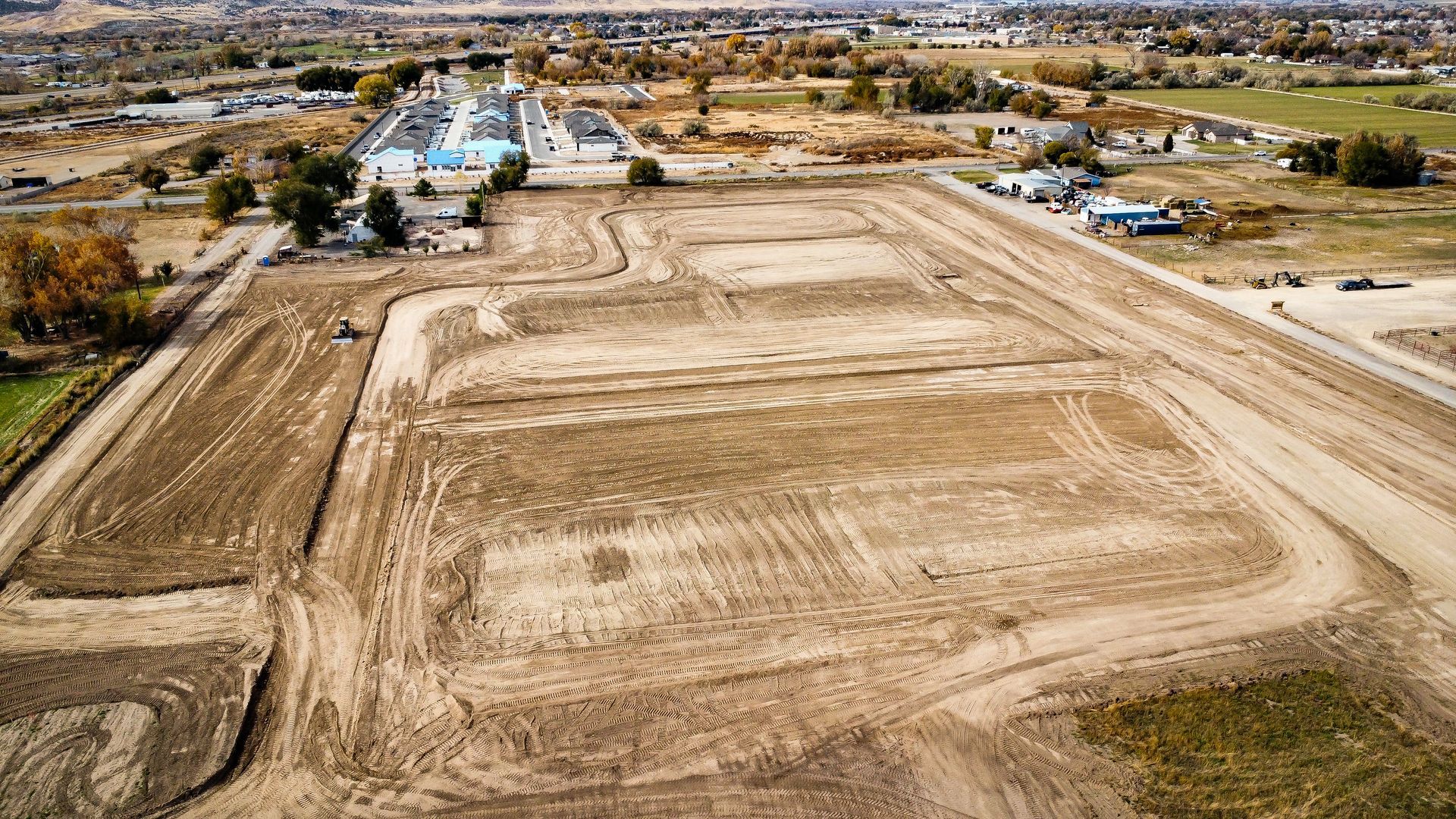 An aerial view of a dirt field with a building in the background.