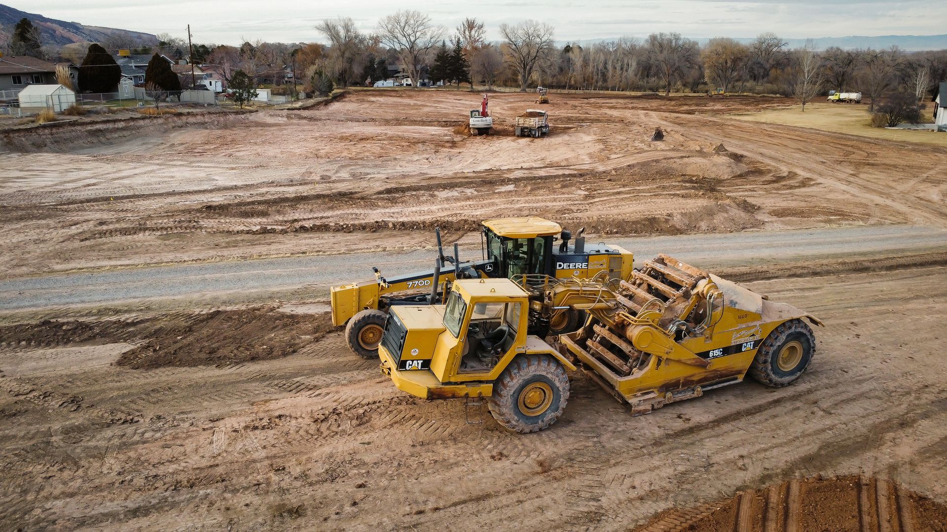 A couple of bulldozers are driving down a dirt road.