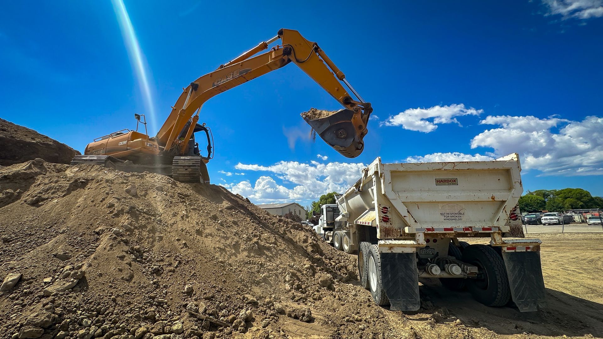 An excavator is loading dirt into a dump truck at a construction site.