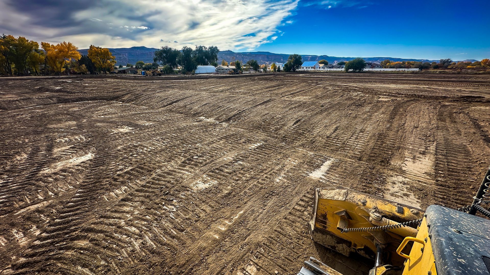 A bulldozer is sitting in the middle of a dirt field.