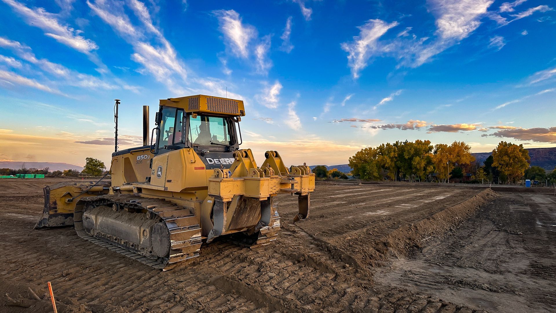 A bulldozer is sitting in the middle of a dirt field.