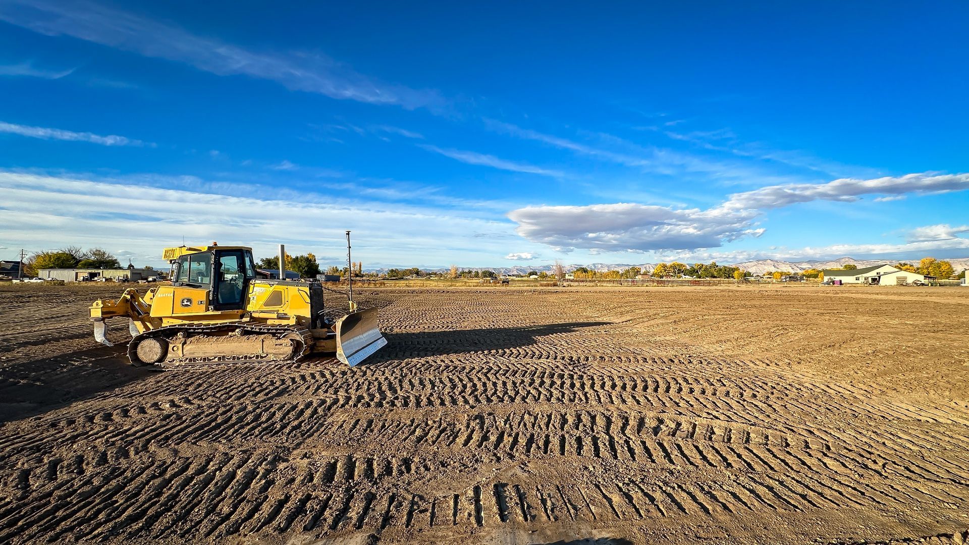 A bulldozer is sitting in the middle of a dirt field.