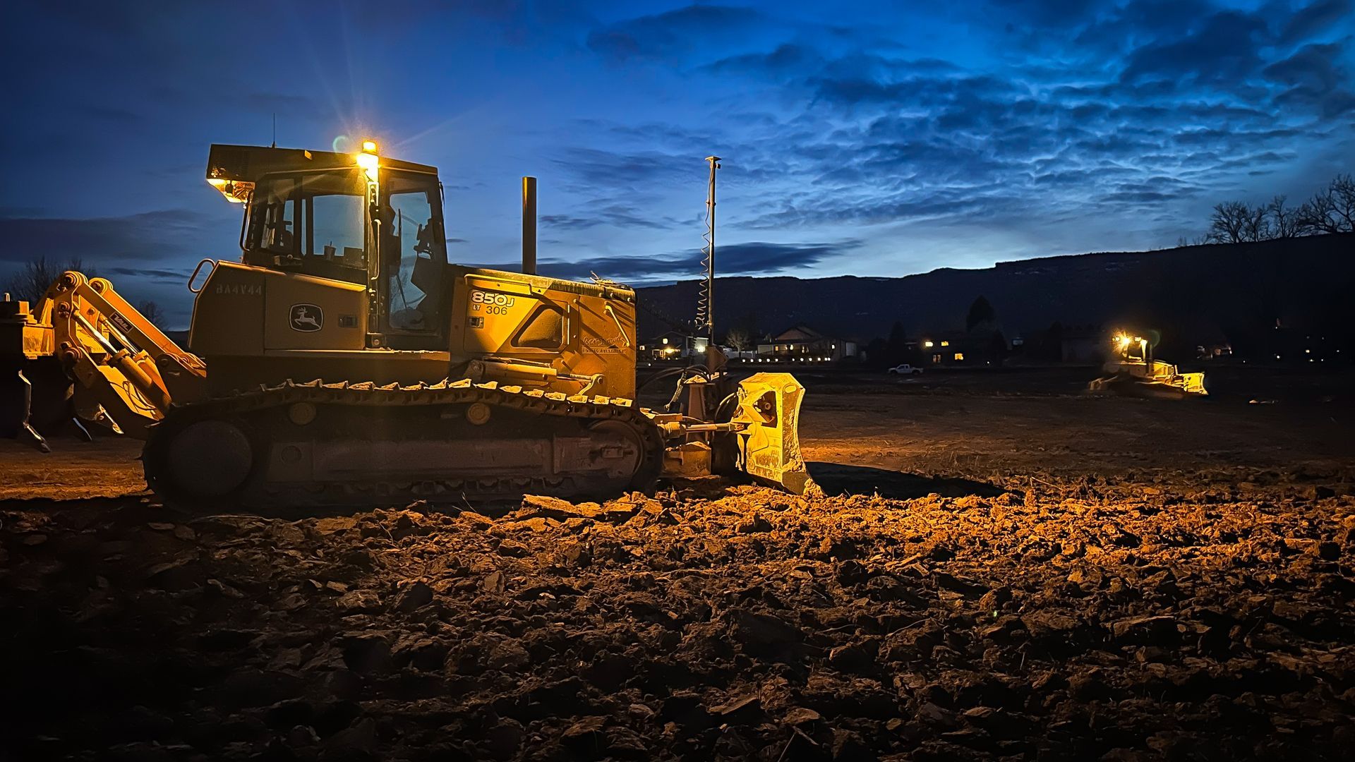 A bulldozer is sitting in a field at night.