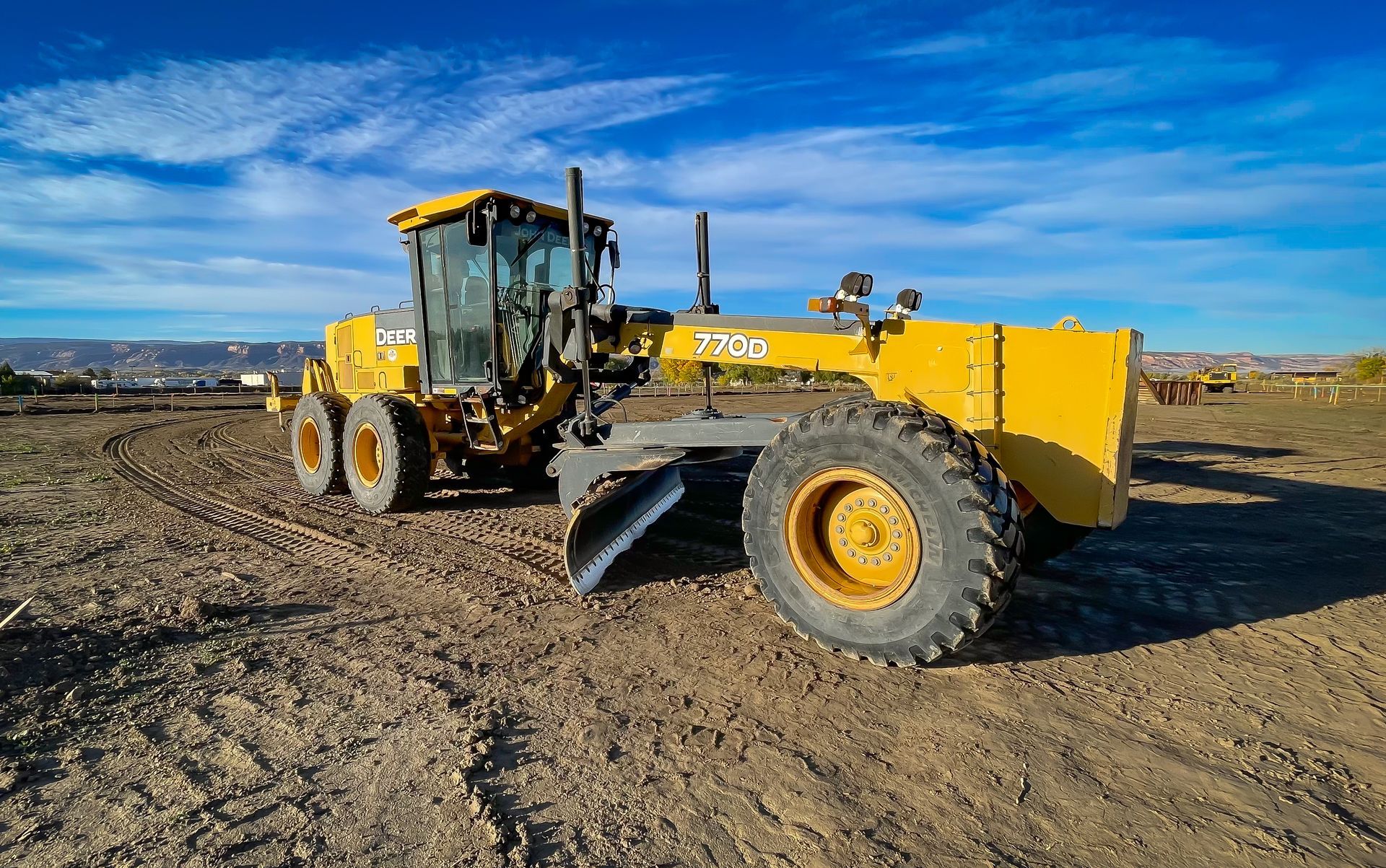 A yellow tractor is sitting on top of a dirt field.