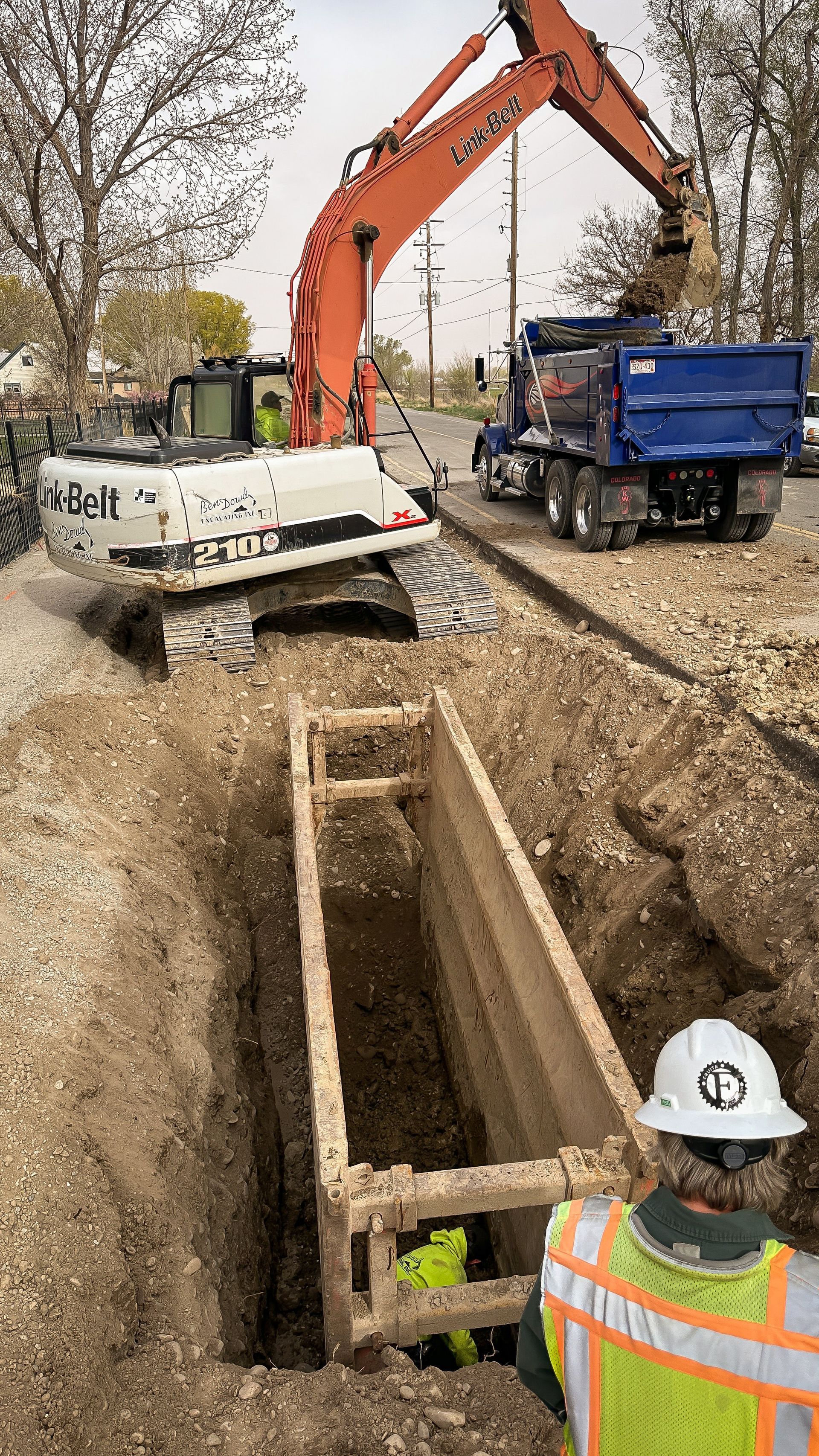 A man in a hard hat is standing next to a large excavator.