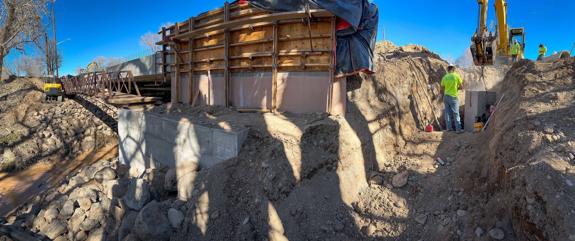 A construction site with a large pile of dirt and a bulldozer in the background.