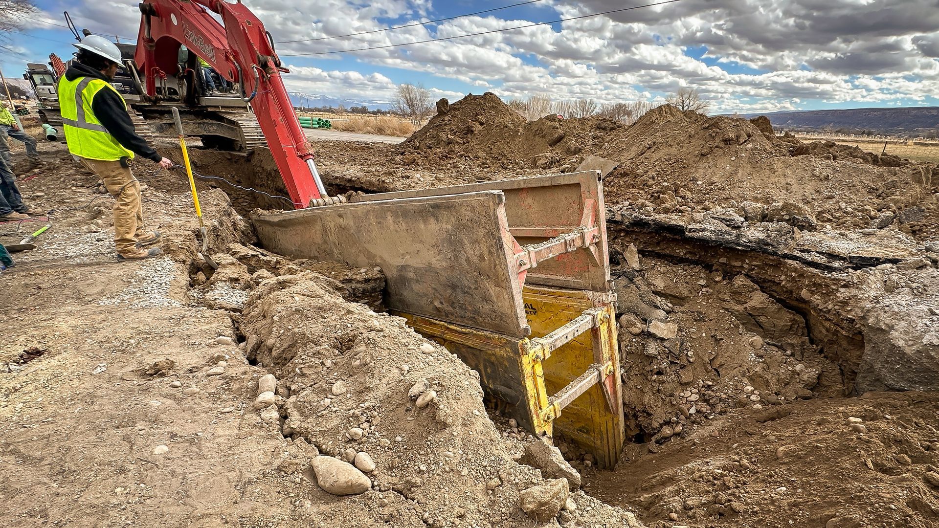 A man is standing next to a bulldozer digging a hole in the dirt.