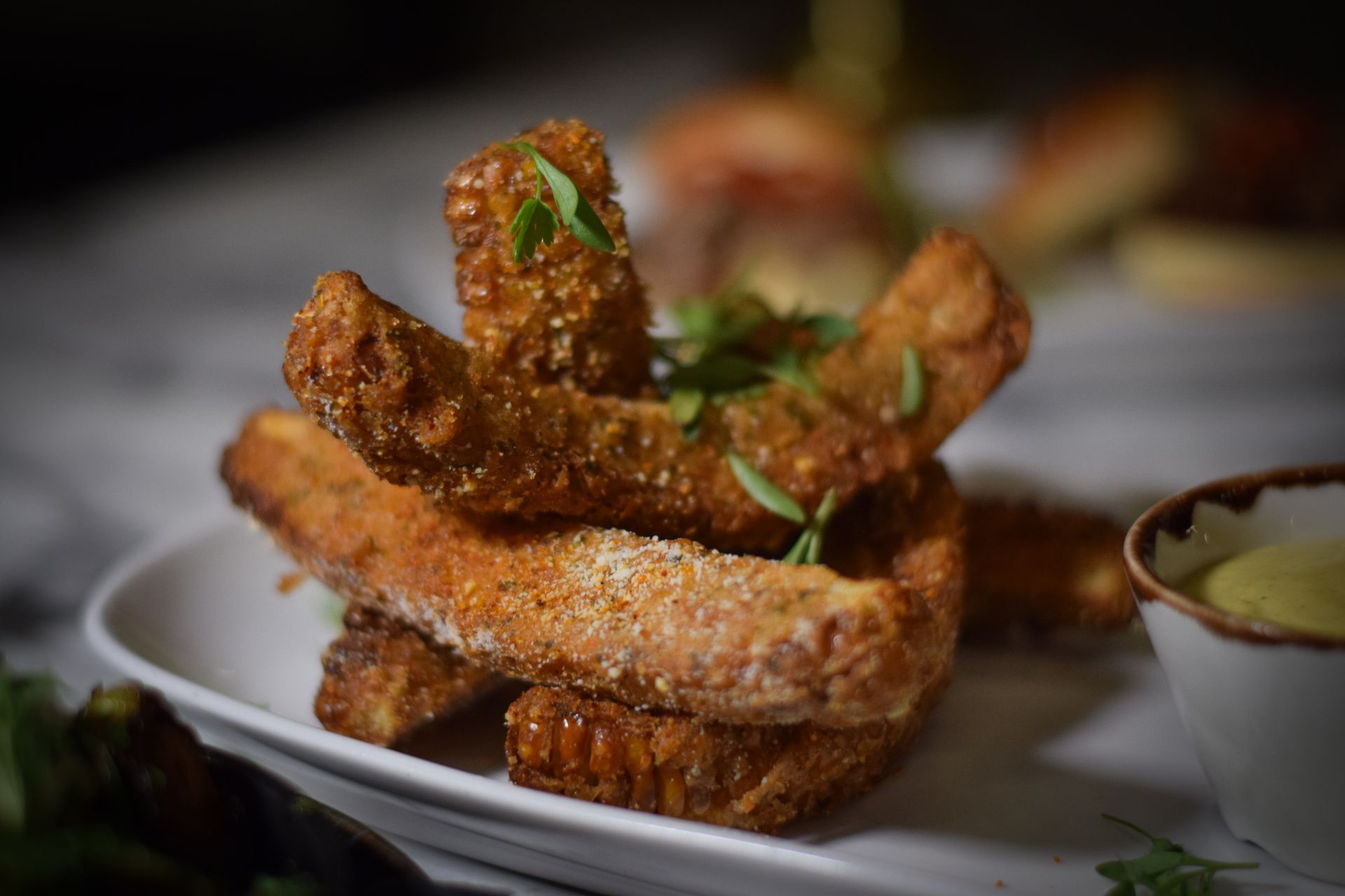 A white plate topped with fried pork chops and a bowl of dipping sauce.