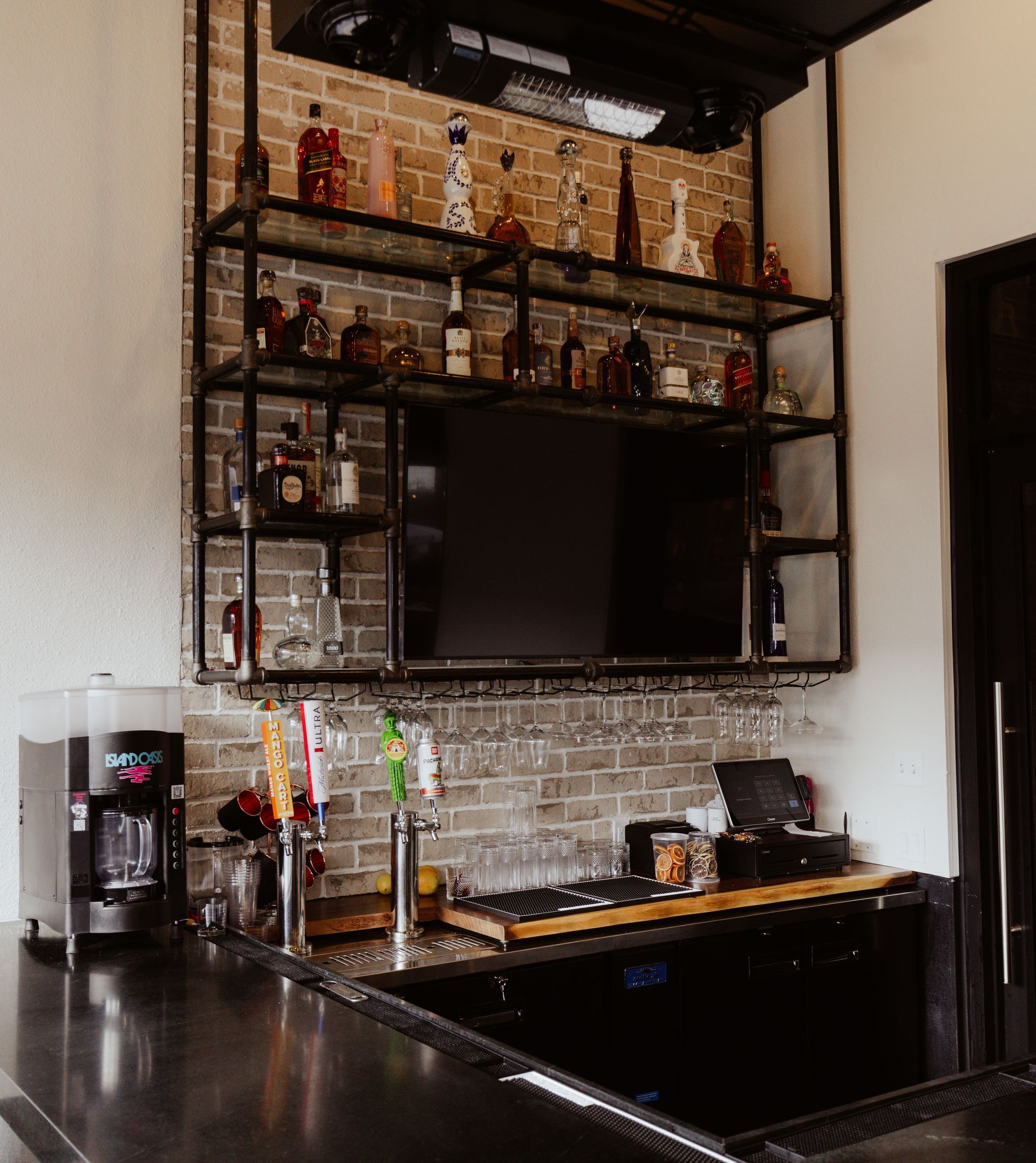 A kitchen with lots of bottles on shelves and a tv