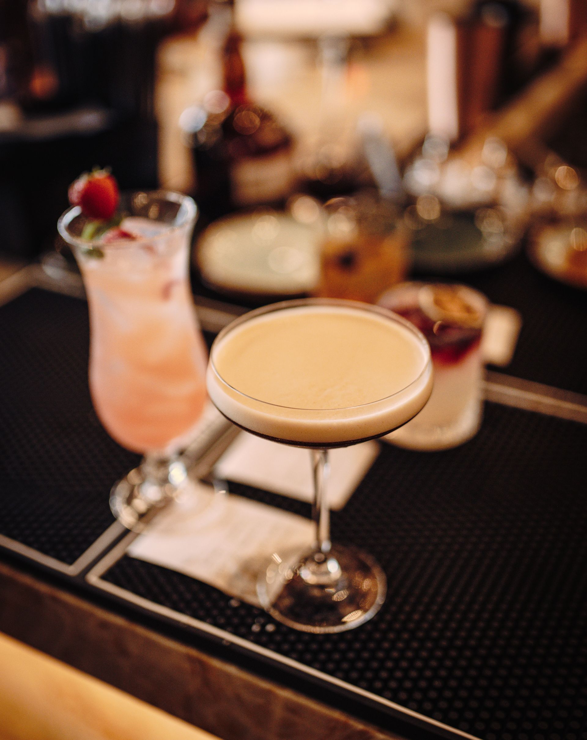 A close up of two cocktails on a bar.