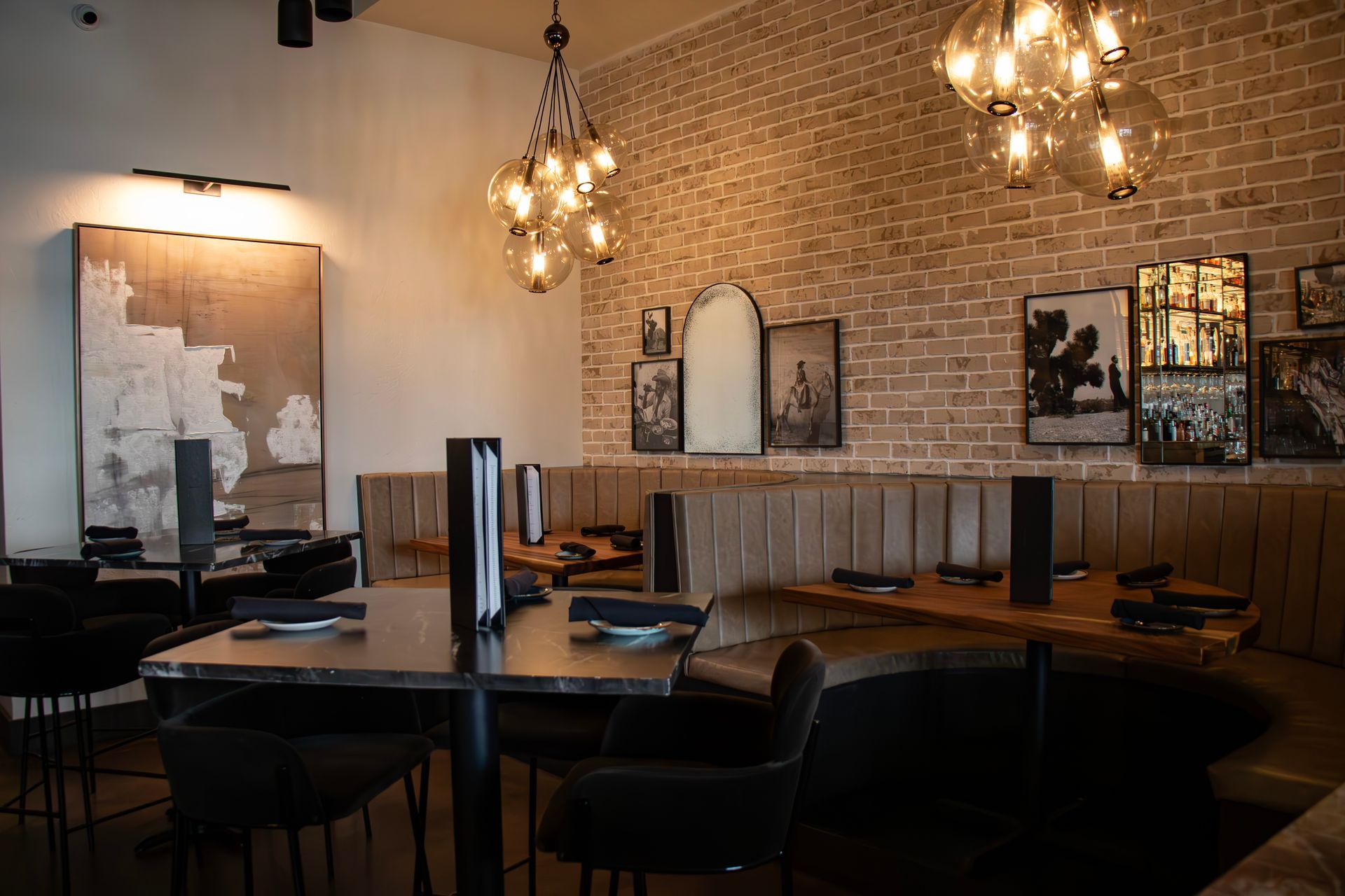 A restaurant with tables and chairs and a brick wall.