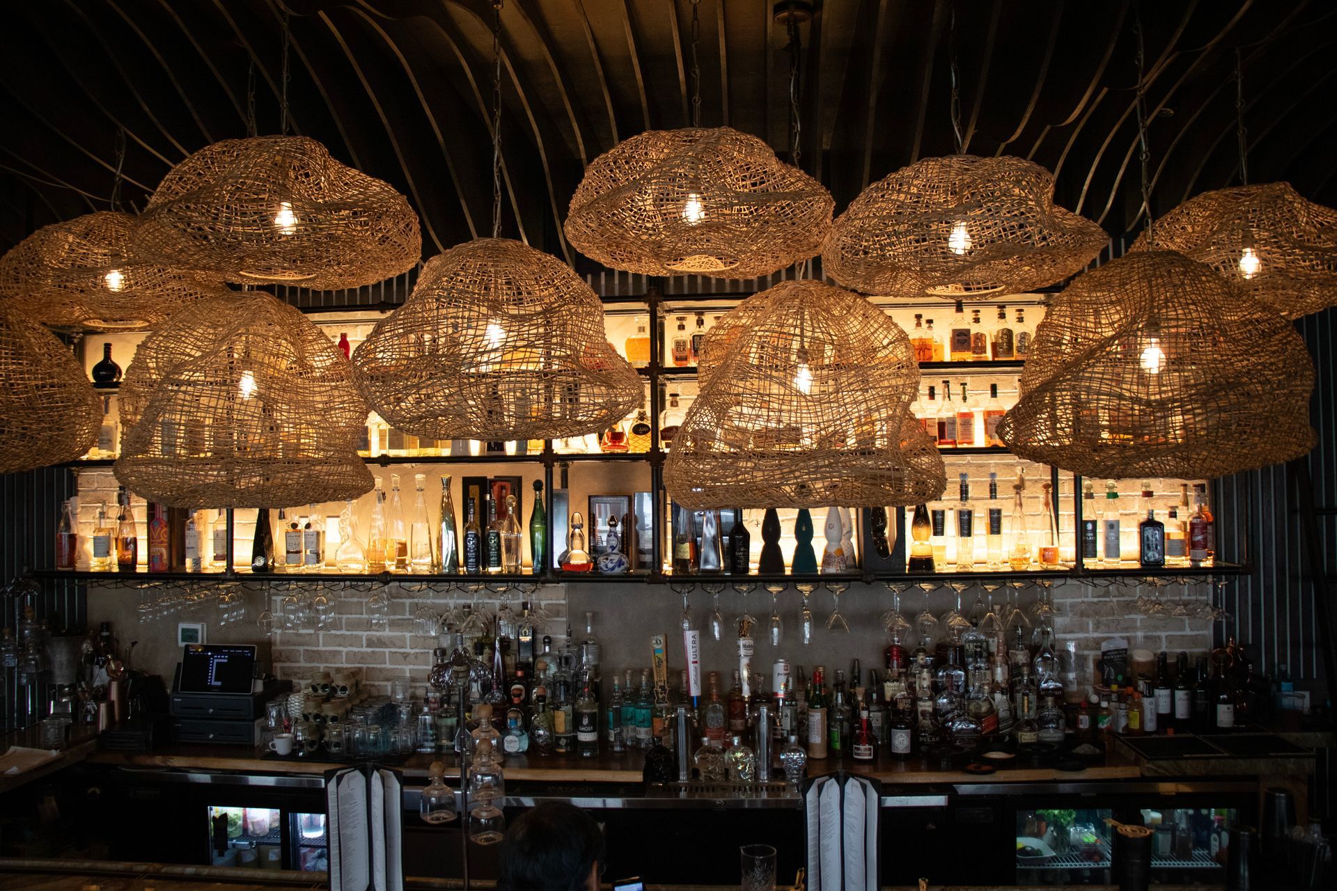 A bar filled with lots of bottles and hanging lights