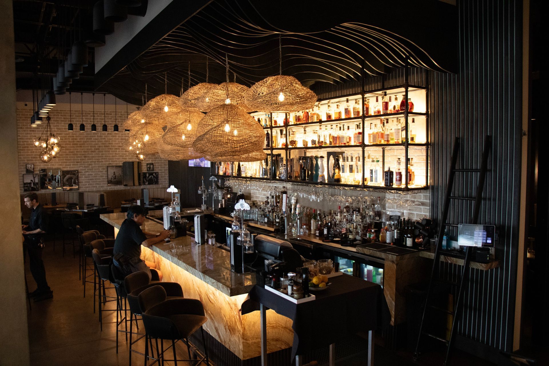 A restaurant with a long bar and lots of bottles on the wall.